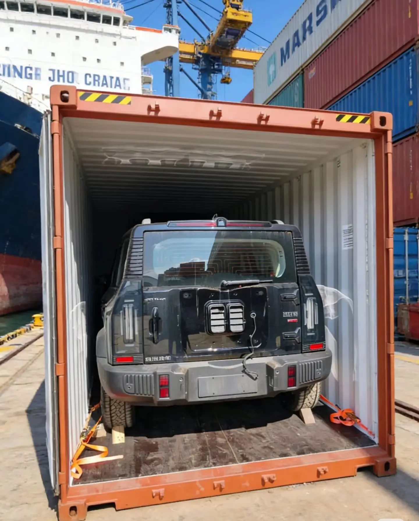 SUV secured with straps inside a shipping container at a port